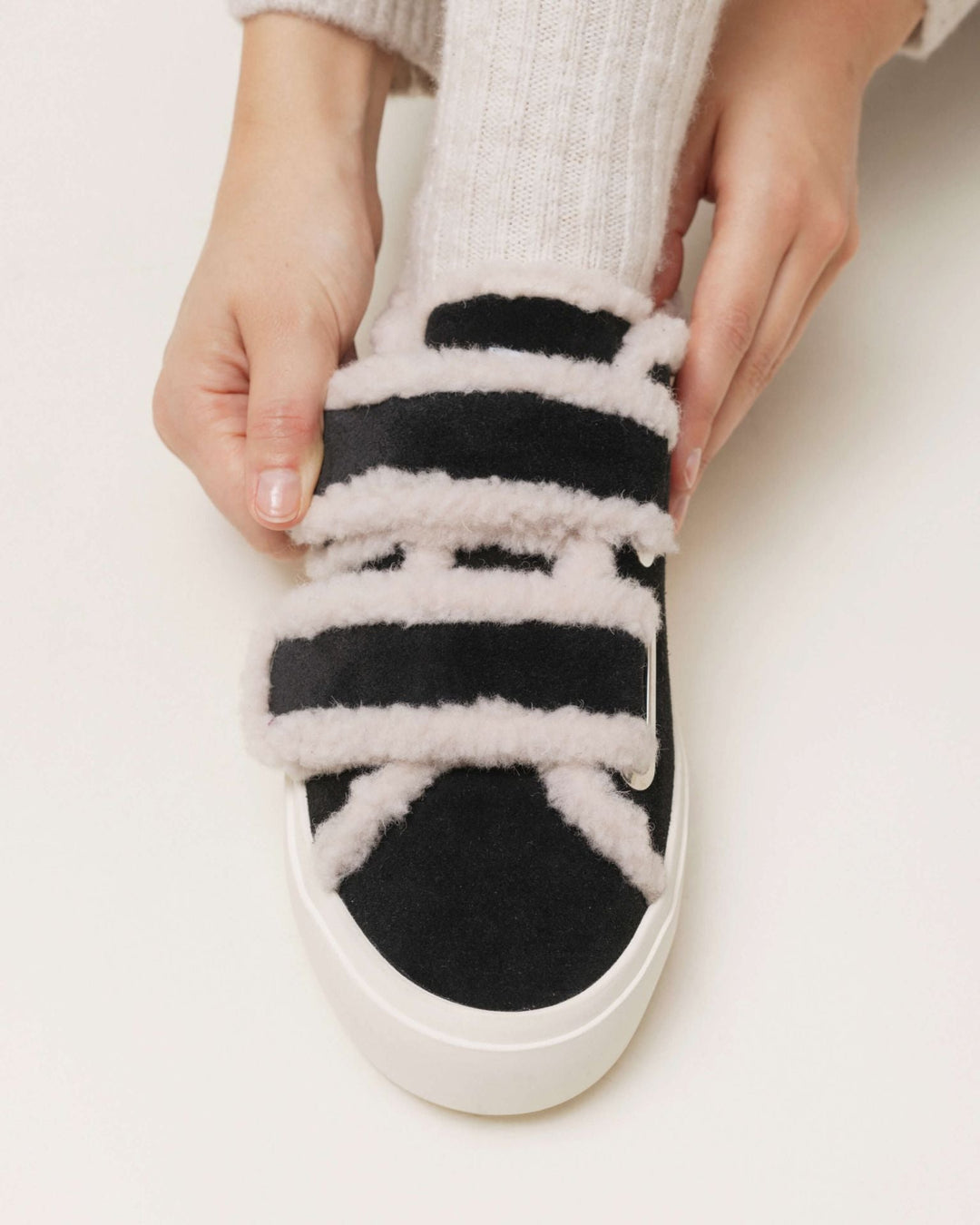 Sort Inuikii sneaker med hvid shearling og velcro, justeret af en hånd, hvid sål.