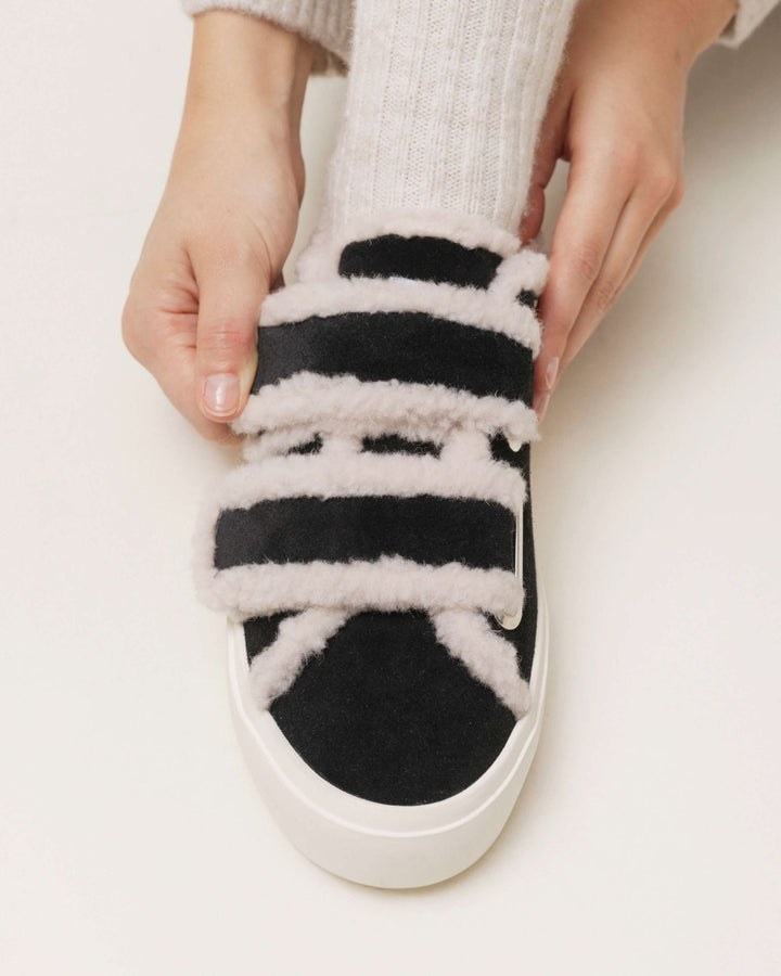 Sort Inuikii sneaker med hvid shearling og velcro, justeret af en hånd, hvid sål.