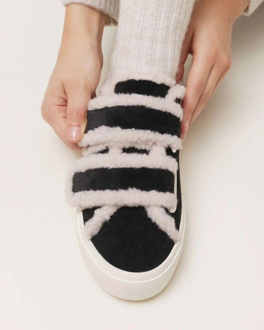 Sort Inuikii sneaker med hvid shearling og velcro, justeret af en hånd, hvid sål.
