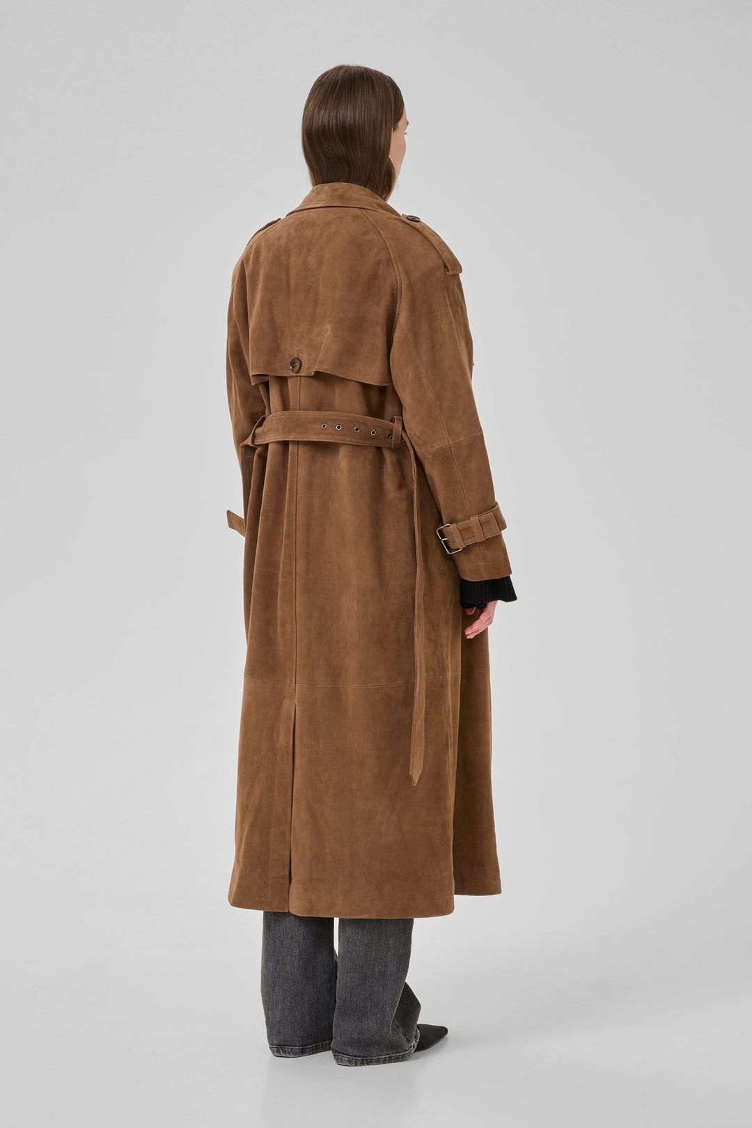 Bagfra visning af cognacfarvet trenchcoat med bælte og epauletter, båret af en person.