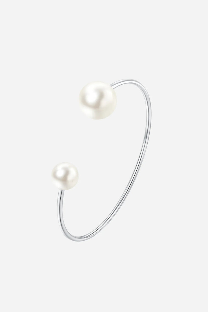 Åbent sølvfarvet armbånd med to perler i forskellige størrelser på hver ende.