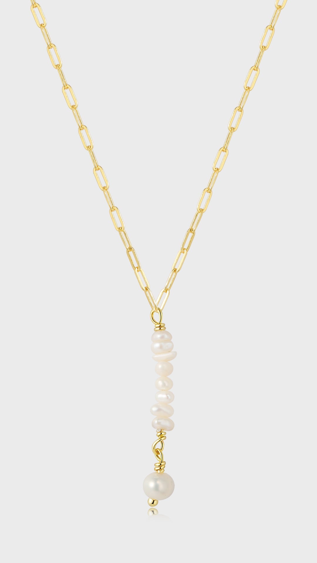 Gylden kæde med aflange led, vedhæng af små hvide perler og en større hvid perle, elegant design.