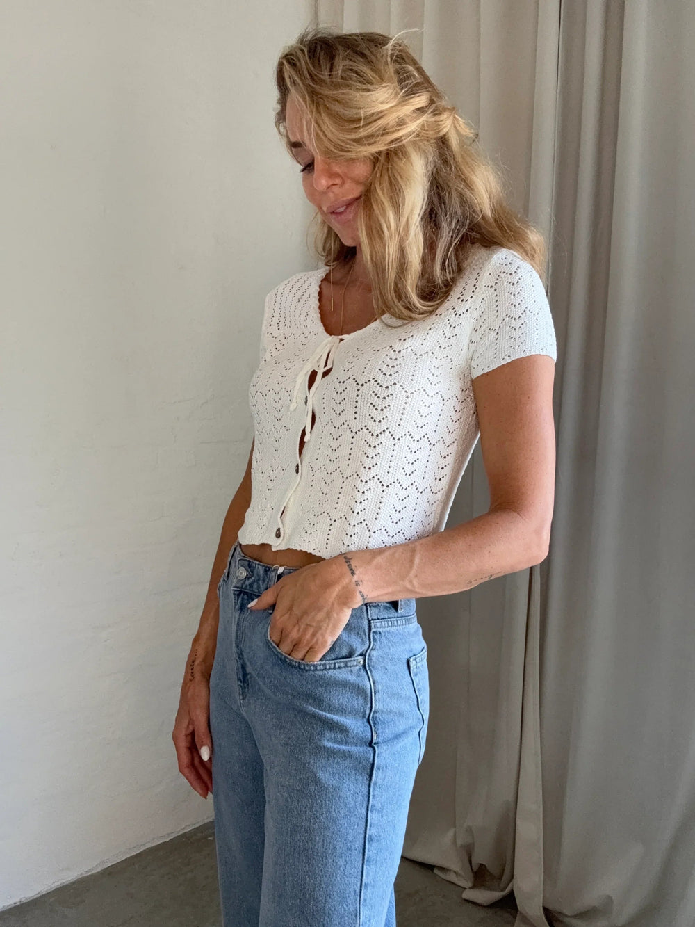 Kvinde i hvid strikket top med blonde, knapper foran, korte ærmer, afslappet pasform.