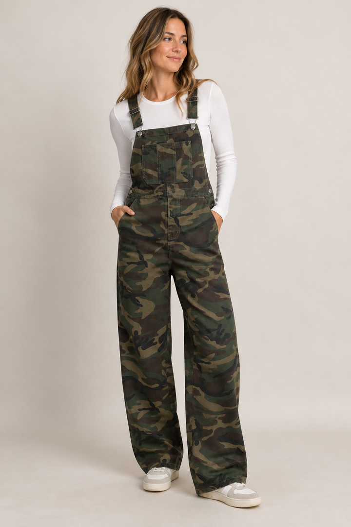 Sassy Heidi overalls i camouflageprint med brede, lige ben, justerbare seler og lommer. Fremstillet i 100% bomuld på mørhåret kvnde med hvis bluse.
