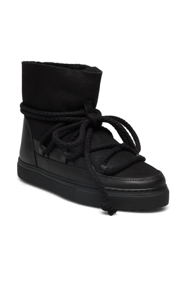 Sort vinterstøvle med højt skaft, tykke snørebånd viklet om og flad, mønstret sål.