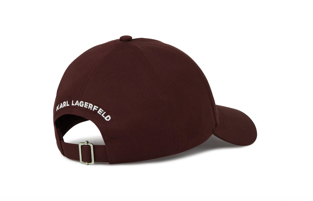 Burgundy kasket med hvid tekst "KARL LAGERFELD" bagpå og justerbar strop med metalspænde.