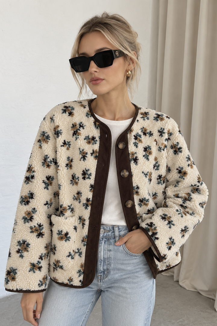 Josefine jakken fra Sassy Copenhagen er en blød og hyggelig teddyjakke med et feminint småblomstret mønster i creme, brun og støvede grønne nuancer på lyshåret kvinde