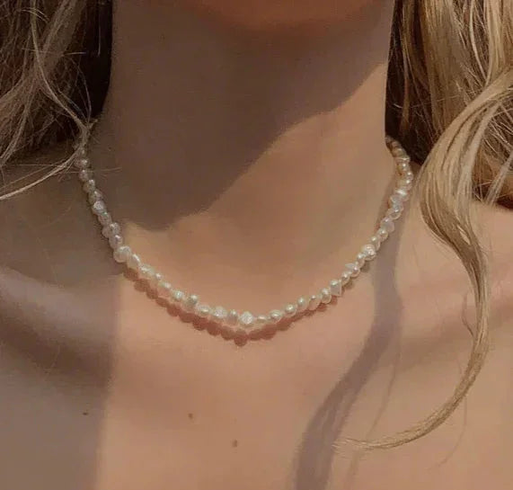 Halskæde af små, hvide perler om halsen på en person, elegant og delikat stil.
