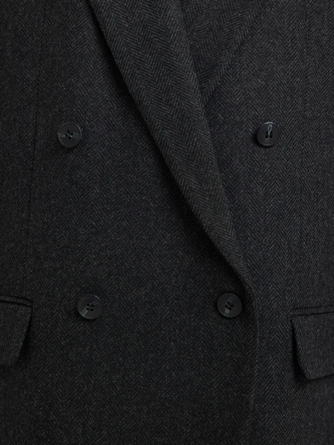 Sort uldblazer med dobbeltknappet design, to lommer foran og subtilt mønster i stoffet.