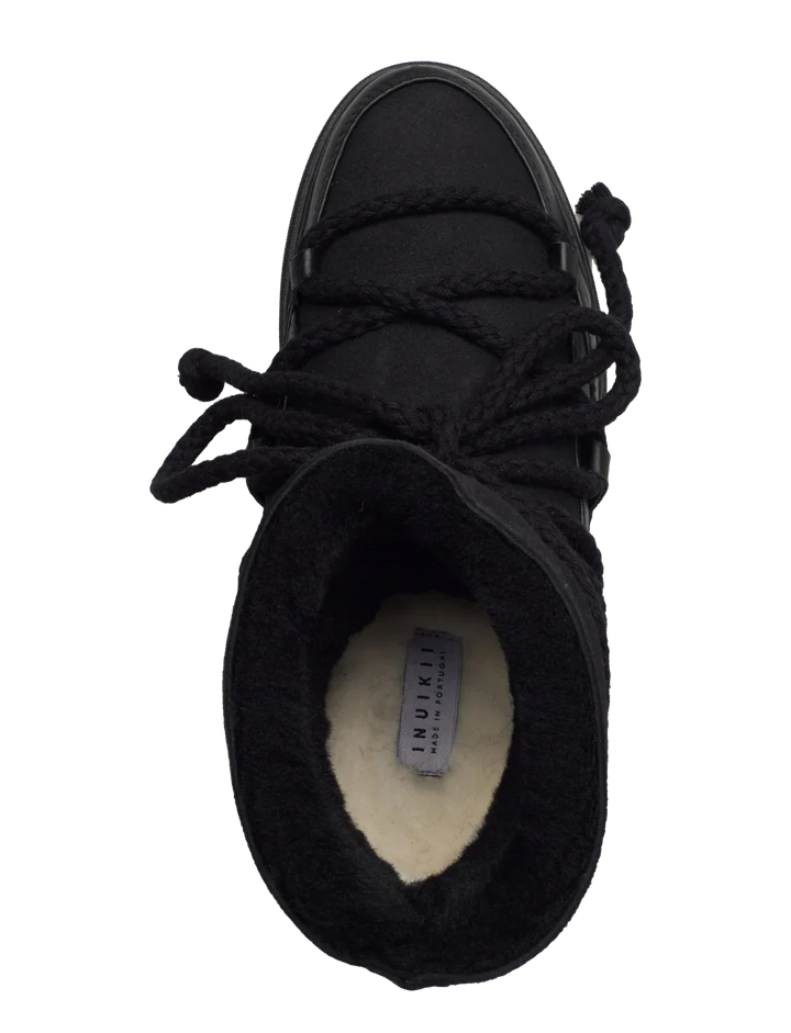 Sort vinterstøvle set oppefra med tykke snørebånd og synlig INUIKII-mærke på indvendig foring.