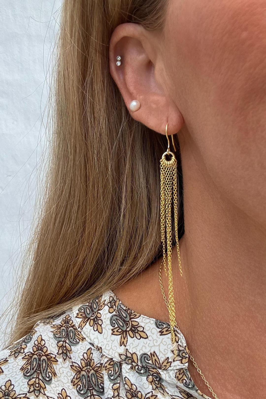 Øreringe med hængende kæder i 18 karat guldbelagt 925 sterlingsølv på et øre.