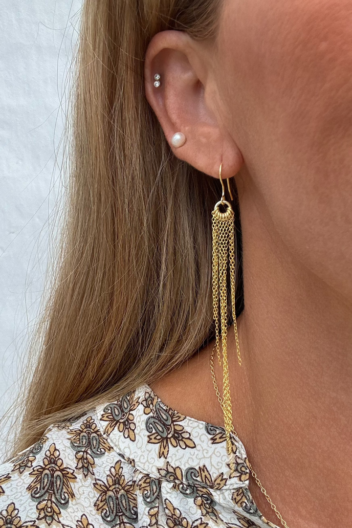 Øreringe med hængende kæder i 18 karat guldbelagt 925 sterlingsølv på et øre.