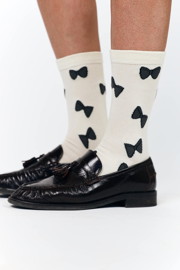 Lollys Laundry BowLL Socks in creme color with black bow patterns, worn by a model, made of cotton blend material.