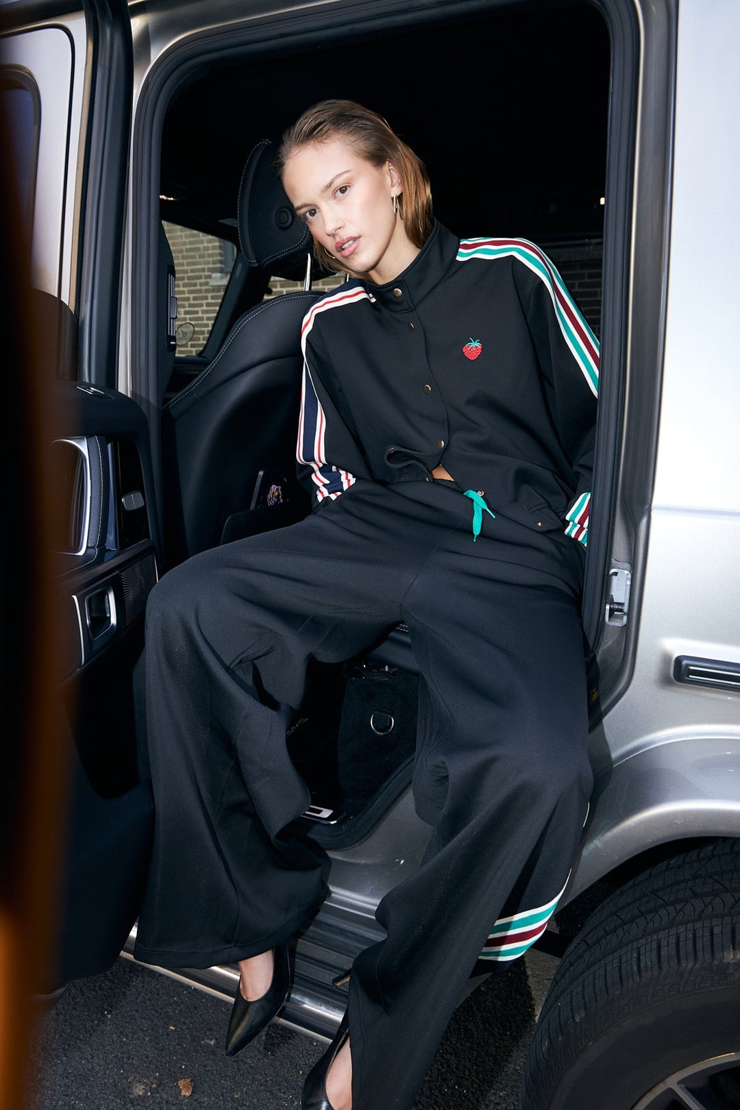 Lollys Laundry BrooklynnLL Short Jacket LS in black, worn by a model sitting in a car, featuring embroidered details.