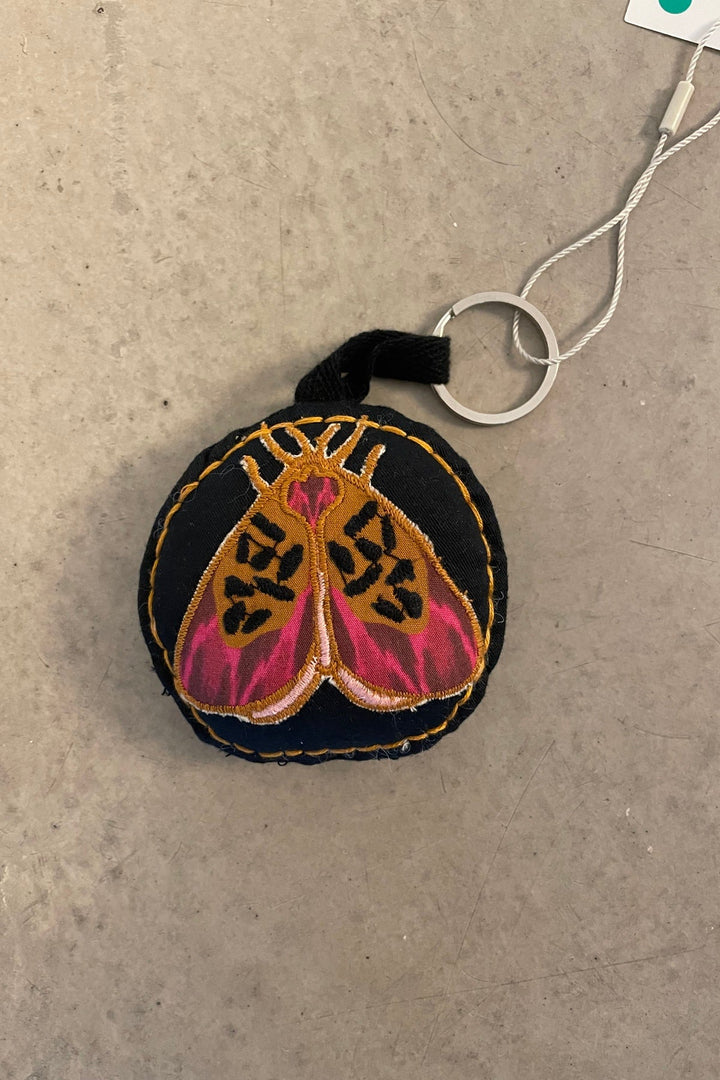Lollys Laundry ButterflyLL Keychain in black cotton with embroidered butterfly design, shown flat on a neutral surface.
