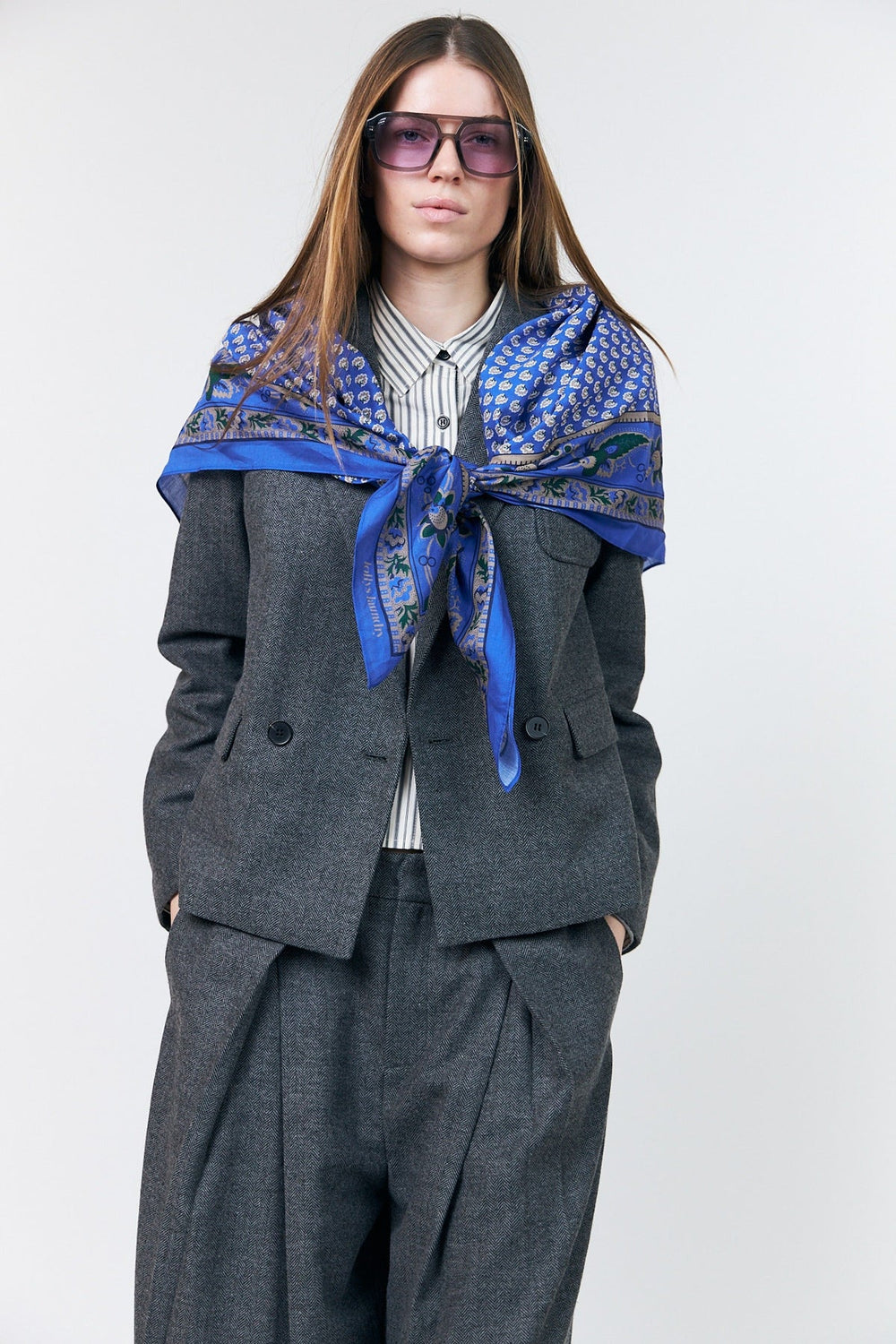 Lollys Laundry JennaLL Big Scarf in blue, made of 100% cotton, styled on a model wearing a gray suit and sunglasses.