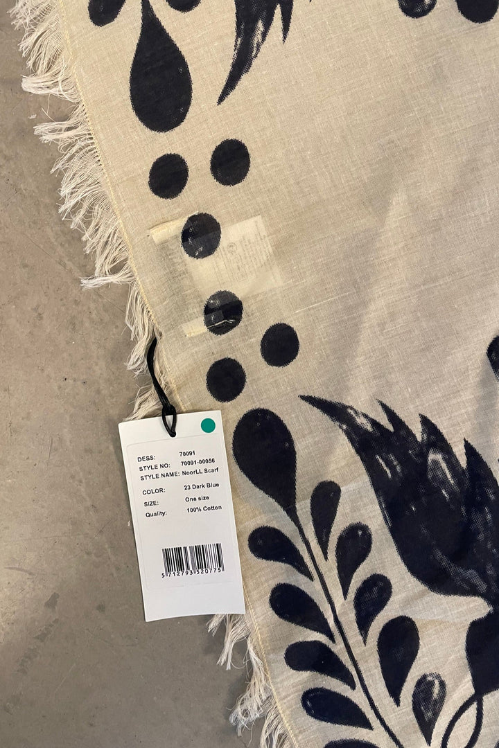 Lollys Laundry NoorLL Scarf in 23 Dark Blue, featuring a floral pattern on a cotton fabric with fringed edges, shown flat.