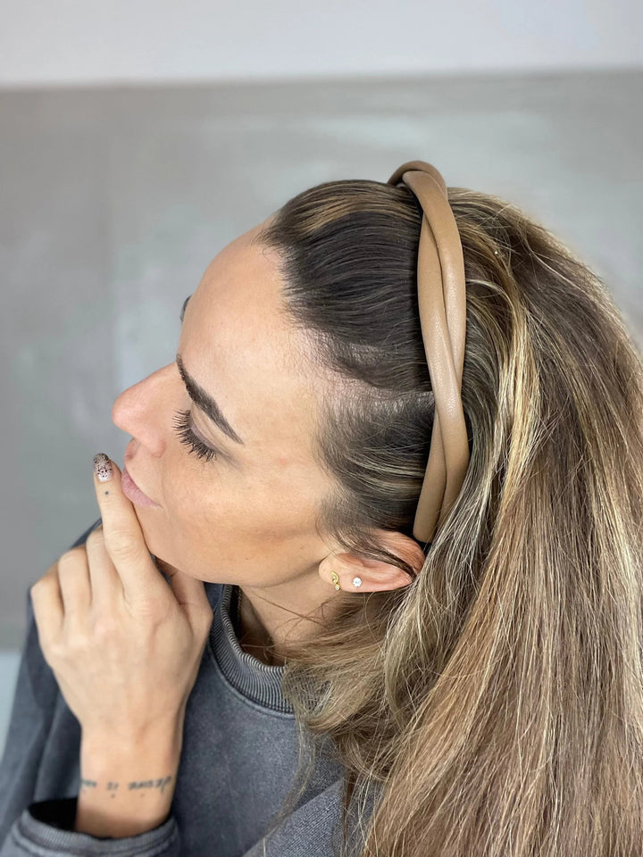 Kvinde med cognacfarvet, smal, flettet læder hårbøjle, set fra siden.