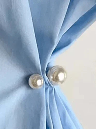 Perle nål fra Andcopenhagen Jewelry bruges som spænde til at samle lyseblåt stof.