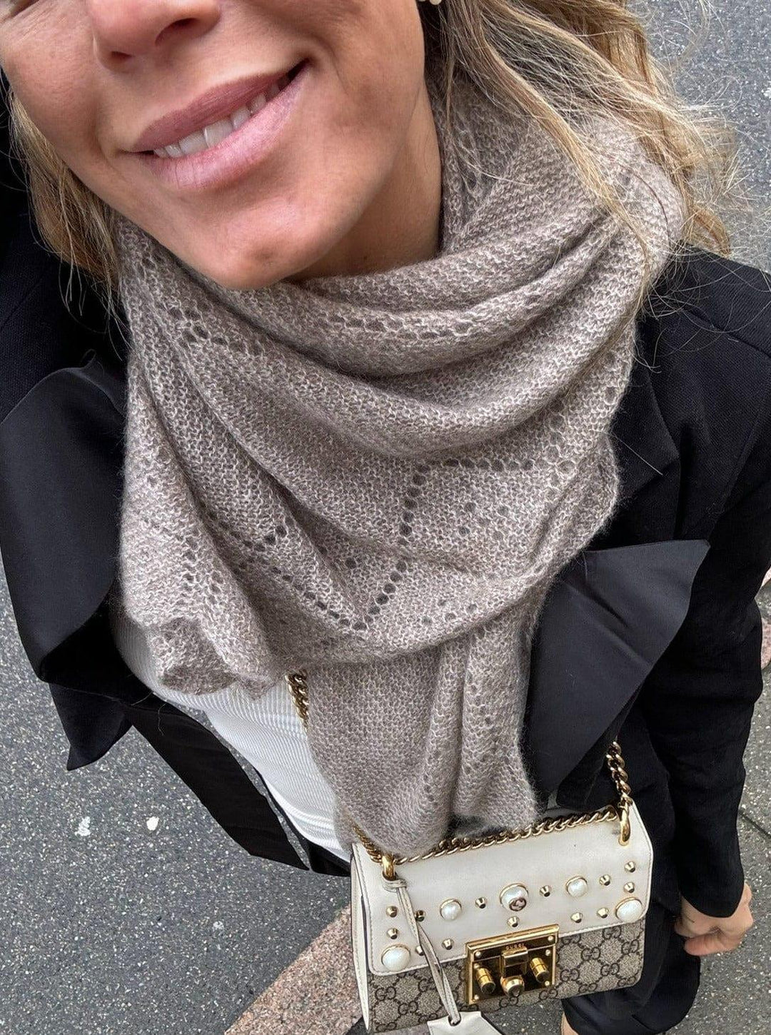 Khaki cashmeretørklæde med lace-mønster, stylet over sort jakke og hvid top. Dekorativ taske ses.